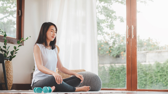 Woman sitting cross legged on the floor doing a meditation